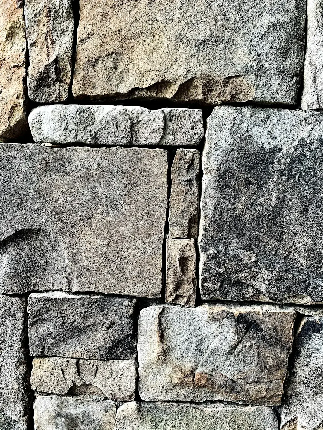 Rows of upright natural stone slabs stored in a lit warehouse yard